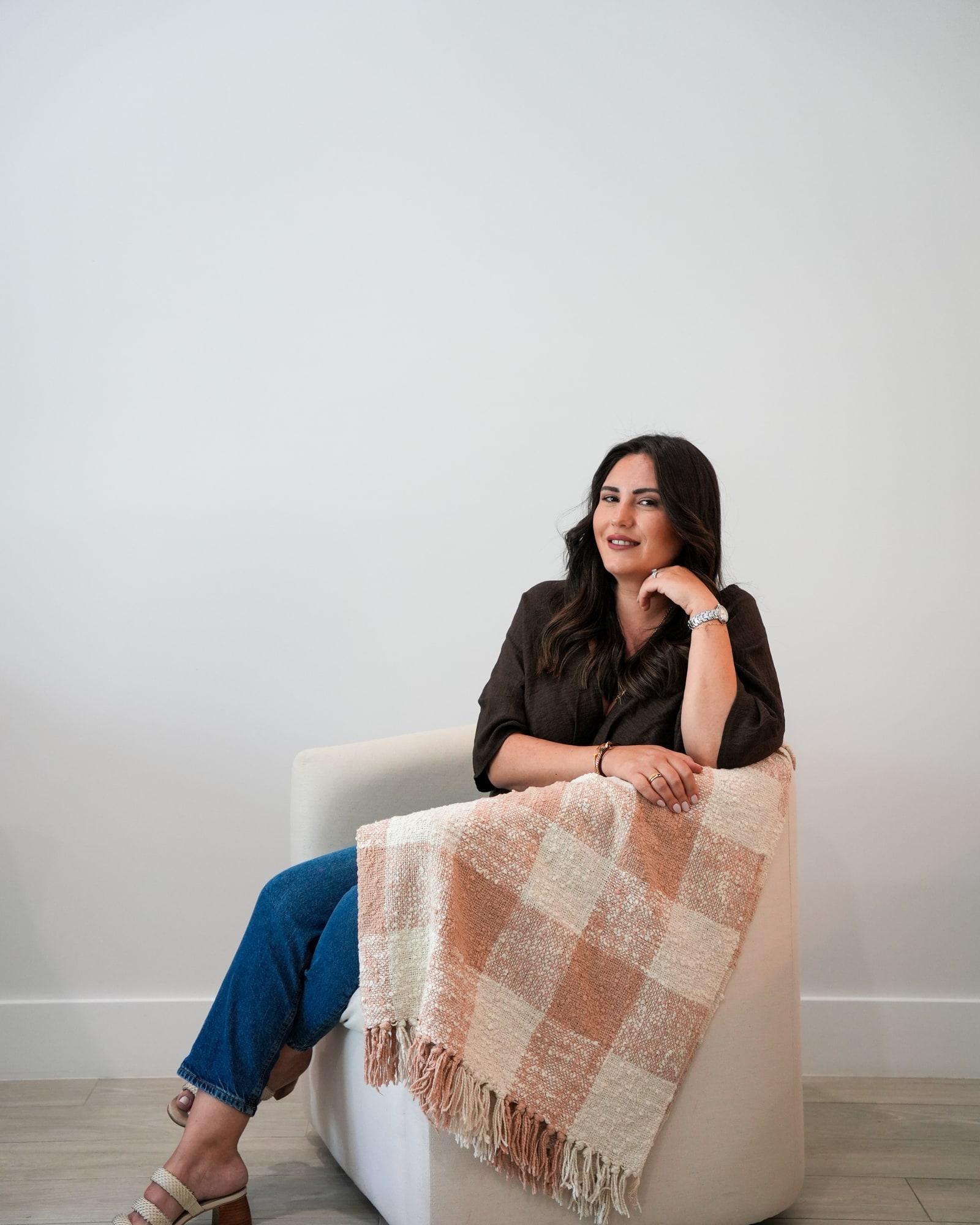 Nadine Donohoe, founder of Nadine Donohoe Interiors, seated in a pale armchair.