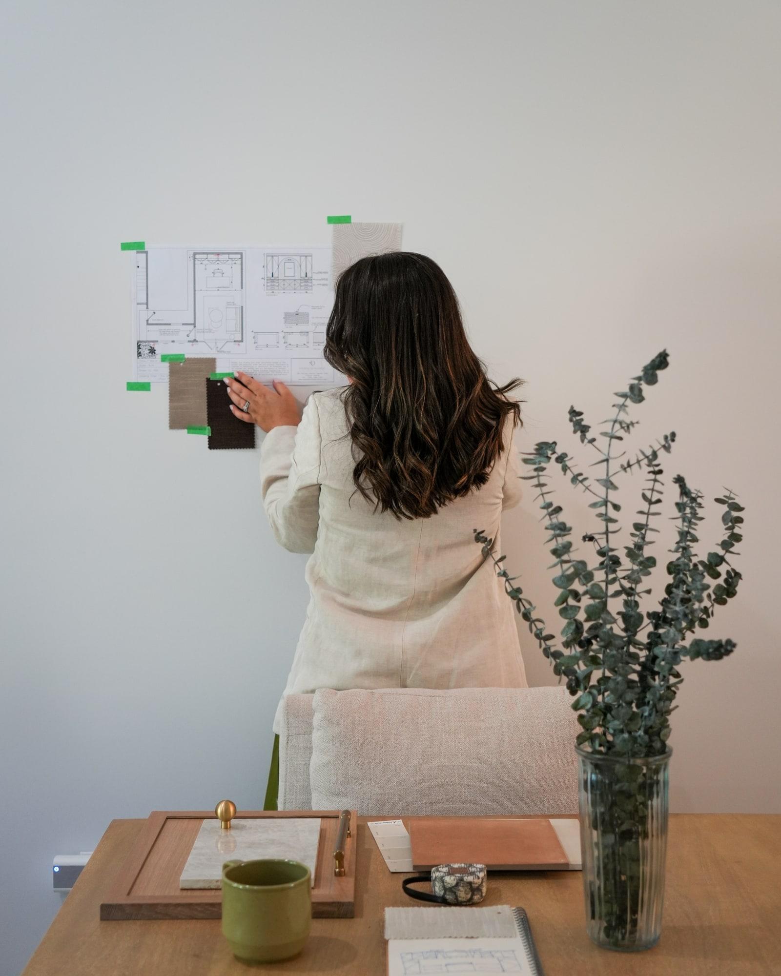 Nadine Donohoe arranging material samples and a floor plan on the studio wall.